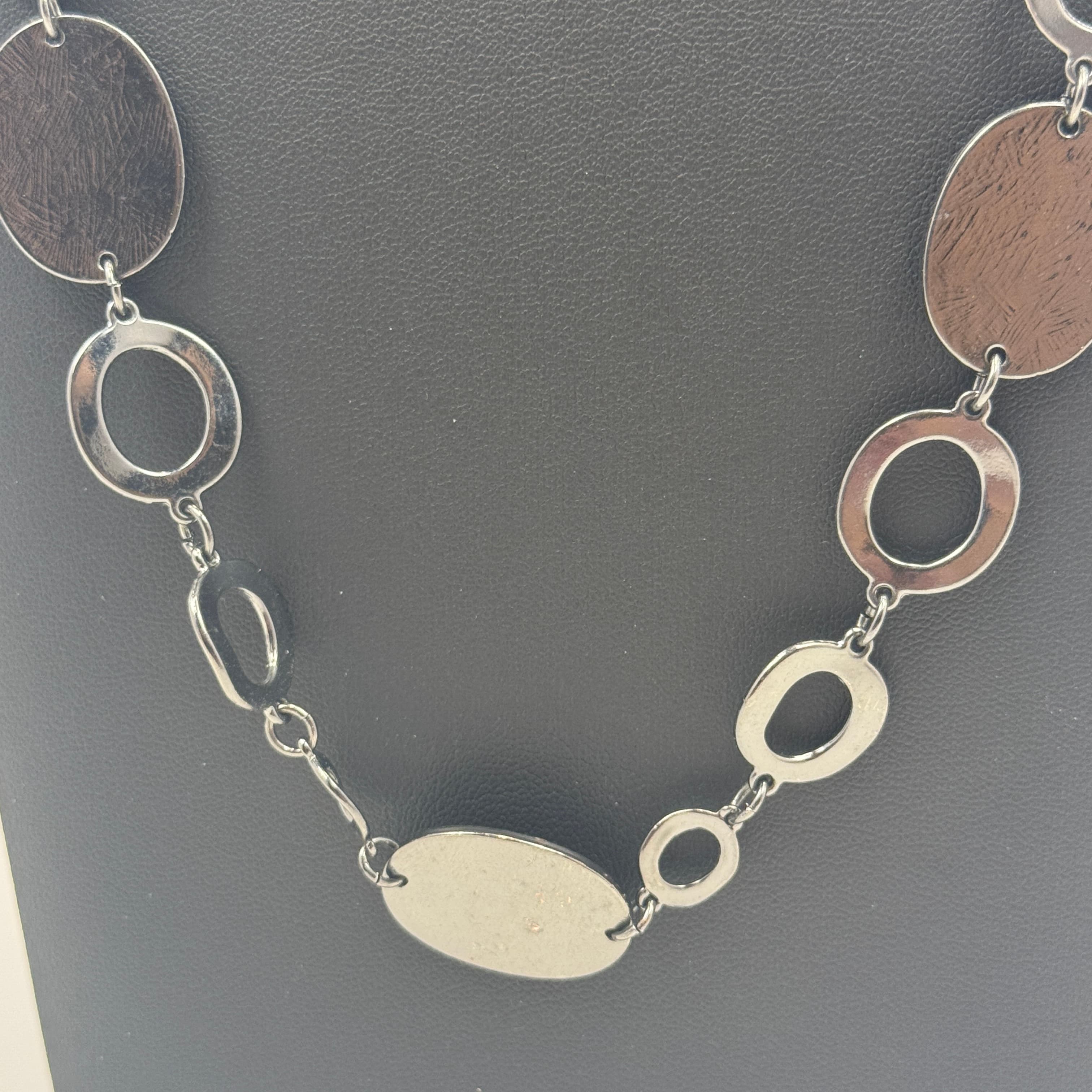<p><strong>Brand:</strong> Chico's (signed with Chico's hang tag near clasp)</p><p><strong>Item:</strong> Long station-style link necklace in a dark gunmetal/hematite tone featuring alternating open oval links and flat oval disc stations with a brushed/textured finish. Great modern, minimalist statement piece.</p><p><strong>Approx. Sizing:</strong> Approx. 34 in wearable length plus approx. 3 in extender (measured using ruler photo reference). Discs approx. 1.25 x 0.9 in; open oval links approx. 0.85 x 0.6 in (estimated from photos).</p><p><strong>Closure:</strong> Lobster clasp with extender chain.</p><p><strong>Materials:</strong> Gunmetal-tone metal alloy (no metal purity marks observed).</p><p><strong>Condition:</strong> Very good pre-owned condition with light surface scratches and finish wear consistent with gentle use; clasp functions normally.</p><p><em>Photos are part of the description.</em></p>